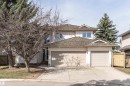 Two-story stucco exterior featuring a two-car garage with individual doors, a concrete driveway, and mature trees - 607 Butterworth Wynd, Edmonton, AB  - Outdoor 