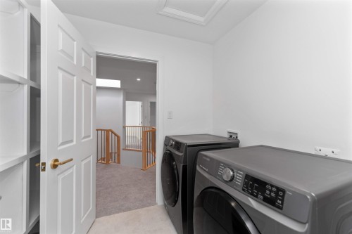 Dedicated laundry area featuring a washer and dryer, adjacent to an entryway with built-in shelving and a paneled door with brass hardware - 607 Butterworth Wynd, Edmonton, AB - Indoor Photo Showing Laundry Room