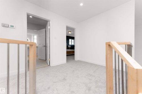 Second-story landing featuring light gray carpeting, crisp white walls, contemporary wood and metal railings, and recessed lighting - 607 Butterworth Wynd, Edmonton, AB - Indoor Photo Showing Other Room