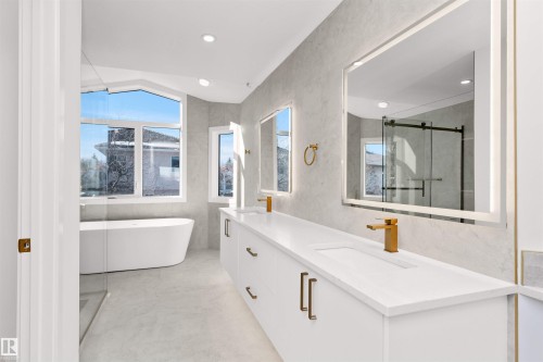 Contemporary bathroom featuring a freestanding soaking tub, a dual vanity with undermount sinks, and gold-finish fixtures - 607 Butterworth Wynd, Edmonton, AB - Indoor Photo Showing Bathroom