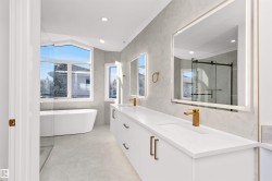 Contemporary bathroom featuring a freestanding soaking tub, a dual vanity with undermount sinks, and gold-finish fixtures - 