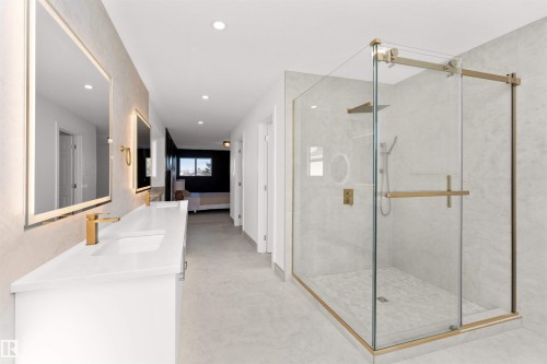 Contemporary bathroom featuring a spacious glass-enclosed shower with gold-toned hardware, a dual-sink vanity with white countertops, and illuminated mirrors - 607 Butterworth Wynd, Edmonton, AB - Indoor