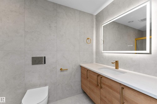 Modern bathroom featuring a wood-finish floating vanity with a white countertop and integrated sink - 607 Butterworth Wynd, Edmonton, AB - Indoor Photo Showing Bathroom