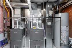 HVAC and water heater utility area featuring two Lennox furnaces, a hot water heater, and extensive ductwork - 