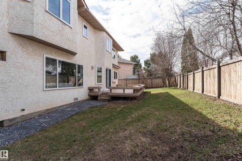 Expansive rear yard featuring a wooden privacy fence, a multi-level wooden deck with built-in seating, and a stone walkway - 607 Butterworth Wynd, Edmonton, AB - Outdoor