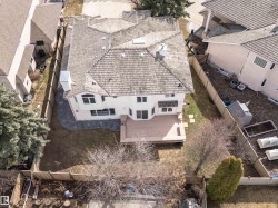 Aerial perspective showcasing a light-colored stucco exterior, a large wood-finish deck, and a multi-level shingle roof - 