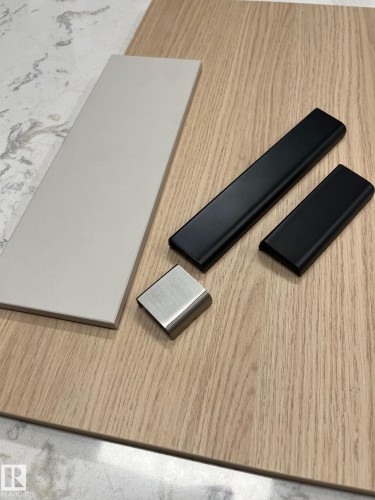 Interior material palette featuring wood-finish cabinetry, solid surface countertop with subtle veining, a light gray rectangular tile, and brushed nickel and matte black hardware options - 9007 92 Street, Edmonton, AB - Indoor Photo Showing Other Room