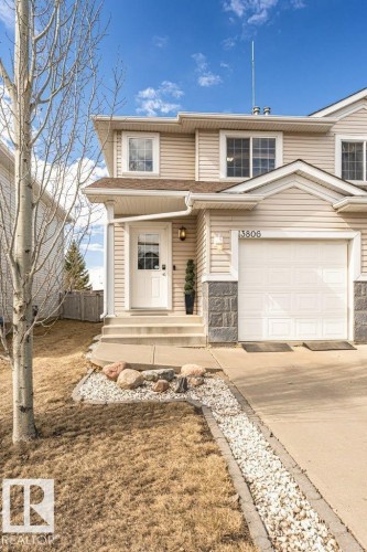 Two-story residence featuring light-colored siding, a white garage door, and a stone-look foundation - 13806 38 Street, Edmonton, AB - Outdoor