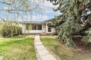 Ranch-style residence featuring white horizontal siding, a sloped shingle roof, a front porch with metal railings, a concrete walkway, and mature evergreen landscaping - 11423 50 Avenue, Edmonton, AB  - Outdoor 