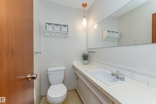 Compact kitchen area featuring wood-finish cabinetry, a stainless steel sink, and white appliances - 11423 50 Avenue, Edmonton, AB - Indoor Photo Showing Laundry Room