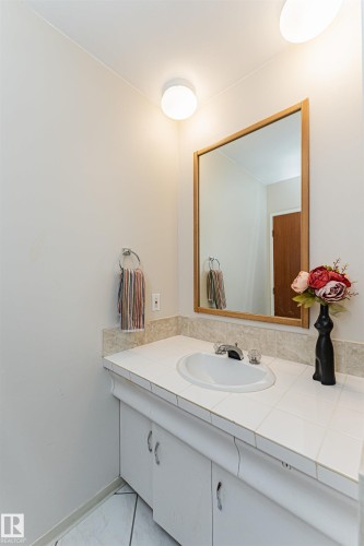 Spacious room featuring a prominent brick fireplace with a black firebox, light-colored carpeting, and neutral wall paint - 11423 50 Avenue, Edmonton, AB - Indoor With Fireplace