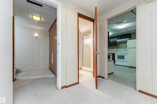 Spacious room featuring light-colored carpeting, white painted walls, and a window with patterned curtains - 11423 50 Avenue, Edmonton, AB - Indoor