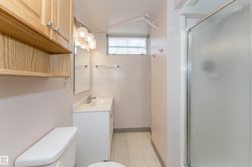 Bathroom featuring a white vanity with integrated sink, chrome faucet, and mirrored wall - 11423 50 Avenue, Edmonton, AB - Indoor