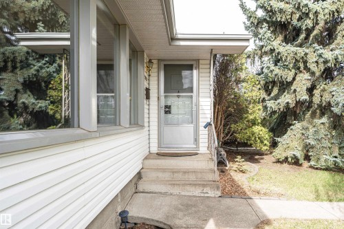 White horizontal siding exterior with a concrete pathway leading to the front entry - 11423 50 Avenue, Edmonton, AB - Outdoor