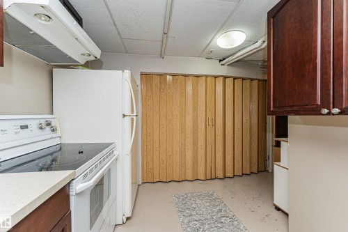 Compact kitchen space featuring a white electric range with a built-in oven, a white refrigerator, and light-toned countertops - 11423 50 Avenue, Edmonton, AB - Indoor Photo Showing Kitchen