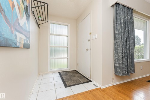 Spacious living area featuring wood-finish flooring, a prominent accent wall, and a large bay window - 11423 50 Avenue, Edmonton, AB - Indoor Photo Showing Other Room