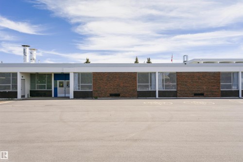 Expansive paved lot fronting a single-story building with a flat roofline - 11423 50 Avenue, Edmonton, AB - Outdoor