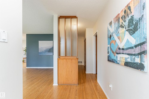 Hardwood flooring extends throughout the living area, complemented by an overhead multi-arm chandelier - 11423 50 Avenue, Edmonton, AB - Indoor Photo Showing Other Room