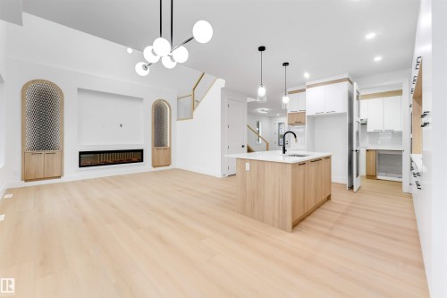 Open-concept living area with light-toned flooring, a modern linear fireplace, and custom built-in cabinetry - 4004 35 Street, Beaumont, AB - Indoor Photo Showing Other Room