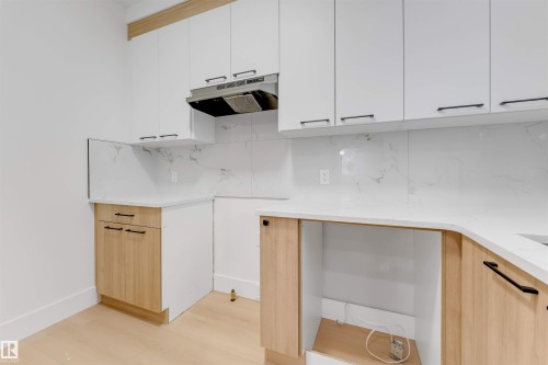 The kitchen features white upper cabinetry, wood-toned lower cabinetry, and white countertops - 4004 35 Street, Beaumont, AB - Indoor Photo Showing Kitchen