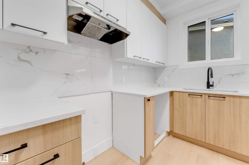 This kitchen features white upper cabinetry, light wood lower cabinetry, and white countertops - 4004 35 Street, Beaumont, AB - Indoor