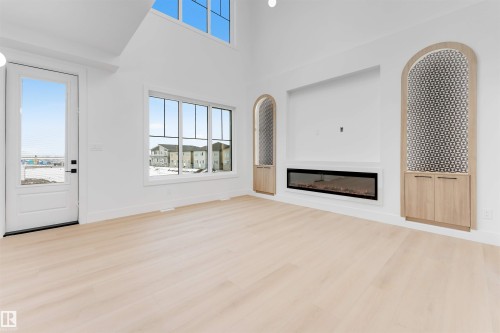Living area featuring light-colored flooring, a large window, and an electric fireplace - 4004 35 Street, Beaumont, AB - Indoor With Fireplace