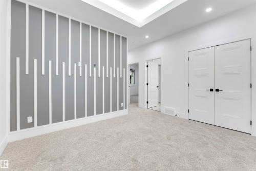 Spacious room featuring light-colored carpet, a decorative accent wall with vertical white trim, and a tray ceiling with recessed lighting - 4004 35 Street, Beaumont, AB - Indoor Photo Showing Other Room