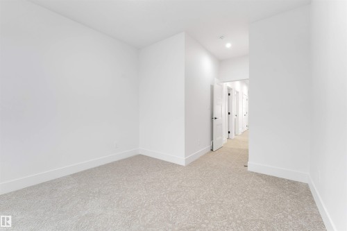 This interior space features light-colored carpeting, white walls, and white baseboards - 4004 35 Street, Beaumont, AB - Indoor Photo Showing Other Room
