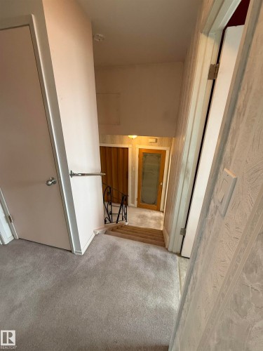 Carpeted hallway with a staircase featuring a wrought iron railing - 12916 95A Street, Edmonton, AB - Indoor Photo Showing Other Room