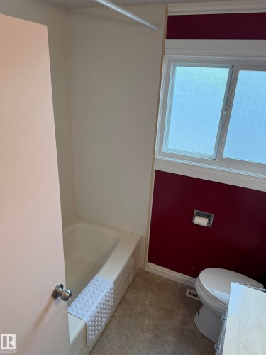 Bathroom featuring a white bathtub, white toilet, and a window with frosted glass - 12916 95A Street, Edmonton, AB - Indoor Photo Showing Bathroom