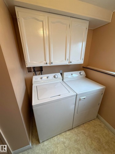 Dedicated laundry area featuring overhead cabinetry, a washer, a dryer, and resilient flooring - 12916 95A Street, Edmonton, AB - Indoor Photo Showing Laundry Room