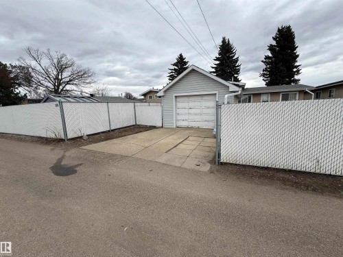 Detached garage with a paneled door and light-toned siding, accompanied by a paved driveway - 12916 95A Street, Edmonton, AB - Outdoor