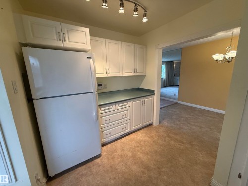 Kitchenette featuring white cabinetry with brushed nickel hardware, light blue countertop, track lighting, and wood-finish flooring - 12916 95A Street, Edmonton, AB - Indoor Photo Showing Kitchen