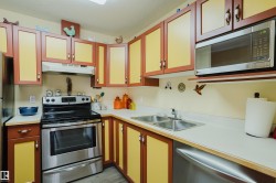 The kitchen features extensive cabinetry, a stainless steel oven with a range hood, a stainless steel microwave, and a double basin sink - 