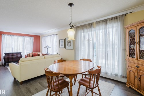 The dining area features a hanging light fixture and wood flooring, with a hutch against the wall - 25 9926 80 Avenue, Edmonton, AB - Indoor Photo Showing Dining Room