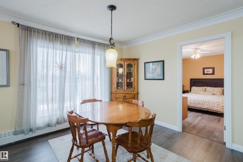 This dining area features light yellow walls, crown molding, and dark flooring - 25 9926 80 Avenue, Edmonton, AB - Indoor Photo Showing Dining Room