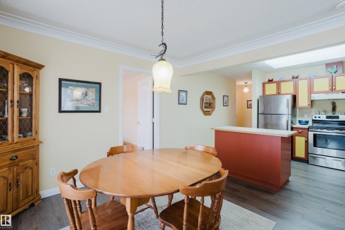 Dining area featuring a pendant light fixture, crown molding, and dark wood-style flooring - 25 9926 80 Avenue, Edmonton, AB - Indoor