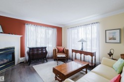 Living area featuring dark flooring, a white mantel with a fireplace, and windows with sheer white curtains - 