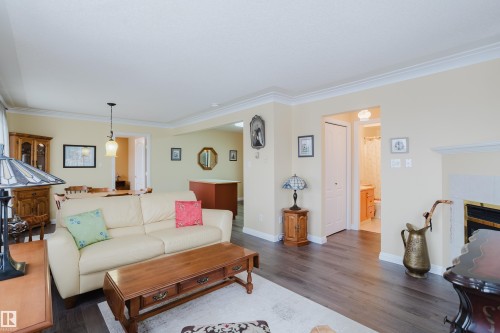 This living area features dark wood flooring, light-colored walls, and white crown molding - 25 9926 80 Avenue, Edmonton, AB - Indoor Photo Showing Living Room