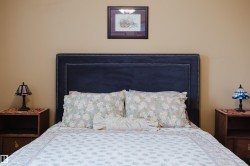 Bedroom featuring a dark upholstered headboard with nailhead trim, and coordinating nightstands with lamps - 