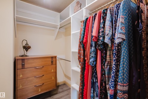 This closet features built-in white shelving, a hanging rail, and wood-look flooring - 25 9926 80 Avenue, Edmonton, AB - Indoor With Storage
