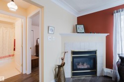 Living area featuring a fireplace with a tiled surround and mantel, wood flooring, and a window with sheer curtains - 
