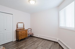 This room features wood-style flooring, a window with blinds, and white bi-fold closet doors - 