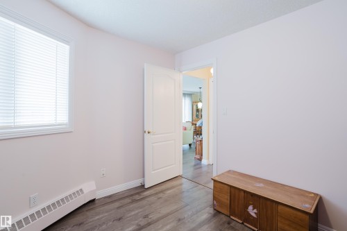 This room features a window with blinds, baseboard heating, and wood-style flooring - 25 9926 80 Avenue, Edmonton, AB - Indoor Photo Showing Other Room