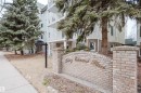 The property features a brick sign with embossed lettering, surrounded by mature evergreen trees - 25 9926 80 Avenue, Edmonton, AB  - Outdoor With Balcony 
