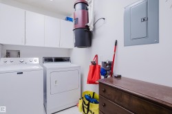 Laundry area featuring white cabinetry, a washer and dryer, and a dark wood chest of drawers - 
