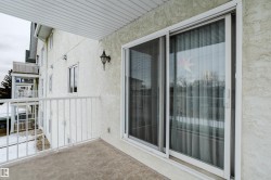 The property features a private balcony with a white railing, a sliding glass door, and an exterior wall lantern - 