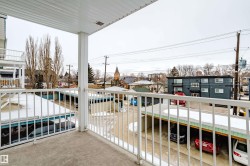 Balcony offering views of the surrounding neighborhood, including a building with a spire, and covered parking areas - 
