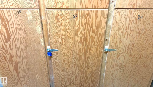 Storage lockers with natural wood grain doors and metal latch hardware - 25 9926 80 Avenue, Edmonton, AB - Indoor Photo Showing Other Room