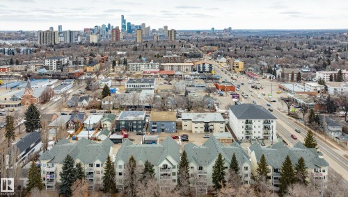 An aerial view showcasing a residential area with a prominent multi-story building featuring balconies and a dark grey roof - 25 9926 80 Avenue, Edmonton, AB - Outdoor With View